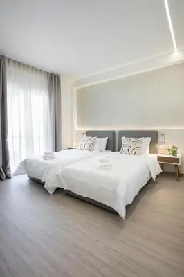 a large bedroom with two beds with white sheets at Deluxe Apartment in Kallithea with Balcony & Wifi in Athens