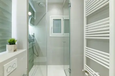 a white bathroom with a shower and a glass door at Urban Elegance 2BR Apartment in Pangrati by UPSTREET in Athens