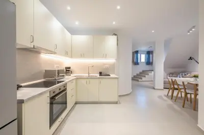 a kitchen with white cabinets and a dining room at The Place to Be Kastella Exclusive in Piraeus