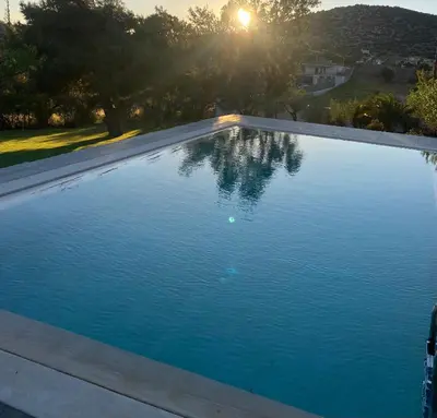 a large blue swimming pool with the sun in the background at RELAXING POOL HOUSE IN LAGONISI 2 in Kalívia Thorikoú