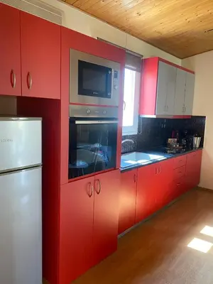 a red kitchen with a refrigerator and a microwave at RELAXING POOL HOUSE IN LAGONISI 2 in Kalívia Thorikoú