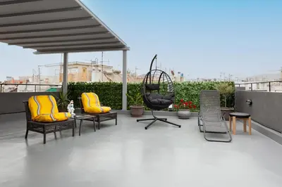 a patio with chairs and a table and a swing at Smart-Stay Acropolis View in Athens