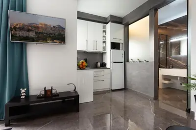 a kitchen with white cabinets and a tv on the wall at Smart-Stay Acropolis View in Athens