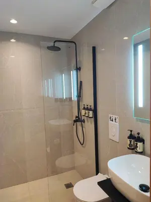 a bathroom with a shower and a toilet and a sink at Regal Hotel Mitropoleos in Athens