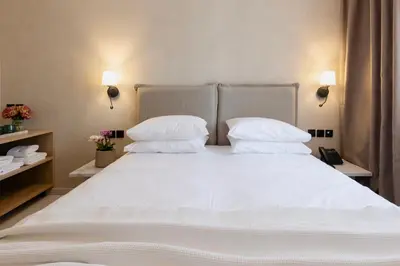 a bed with white sheets and pillows in a room at Regal Hotel Mitropoleos in Athens