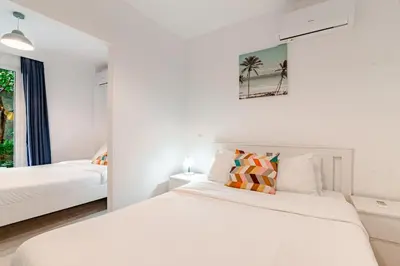 a white bedroom with two beds and a window at Quiet simple brand new luxury apartment by the sea in Athens
