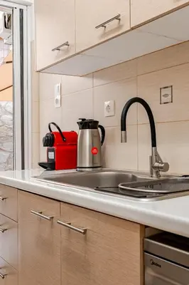 a kitchen with a sink and a red tea kettle at Quiet simple brand new luxury apartment by the sea in Athens