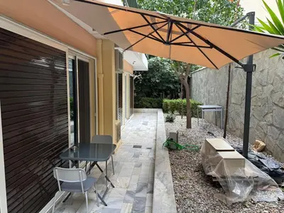 a table and chairs under an umbrella on a patio at Quiet simple brand new luxury apartment by the sea in Athens