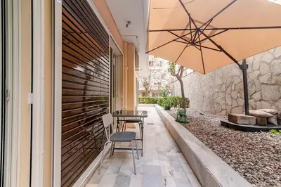 a patio with a table and chairs and an umbrella at Quiet simple brand new luxury apartment by the sea in Athens