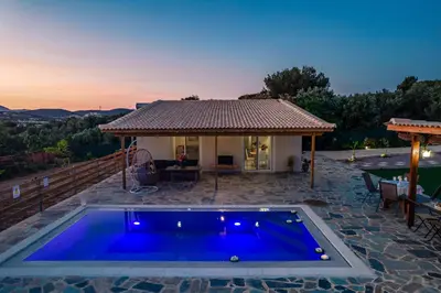 a villa with a blue pool in front of a house at RELAXING POOL HOUSE IN LAGONISI 1 in Kalívia Thorikoú