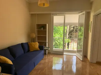 a living room with a blue couch and a sliding glass door at Charming Plaka Retreat in the Heart of Historic old Athens city in Athens