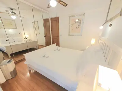 a white bedroom with a bed and a mirror at Kavouri Seaside 85sqm Apartment 5' from the beach in Athens