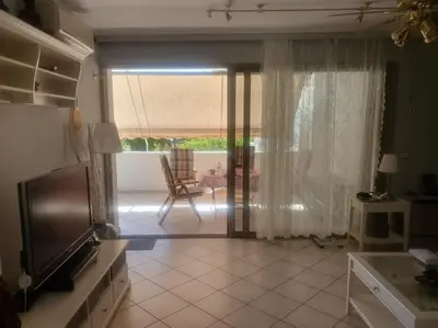 a living room with a television and a sliding glass door at Kavouri Seaside 85sqm Apartment 5' from the beach in Athens