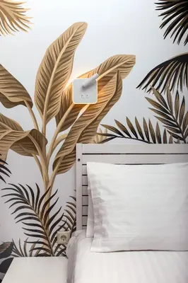 a bedroom with a bed and a mural of tropical leaves at Artemonos Loft Acropolis View in Athens