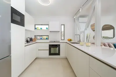 a white kitchen with white cabinets and windows at Vouliagmeni - Apollonos Street in Athens