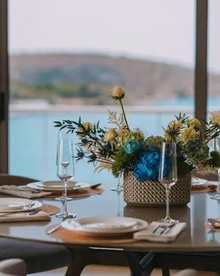 a table with glasses and a vase of flowers at Vouliagmeni - Apollonos Street in Athens