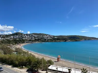 a beach with a lighthouse in the middle of the water at Vouliagmeni - Apollonos Street in Athens