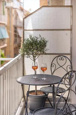 two glasses of wine sitting on a table on a balcony at Comfort Oasis: Work-Friendly Space w/Fiber Net in Athens