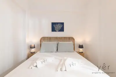 a bedroom with a white bed with two lamps at Shell-Charm w/Sea View & Parking in Piraeus