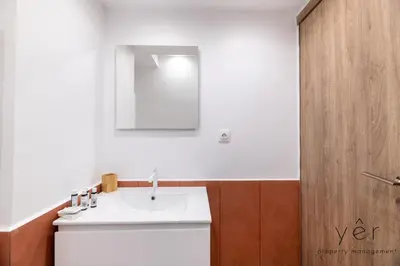 a bathroom with a white sink and a wooden door at Shell-Charm w/Sea View & Parking in Piraeus