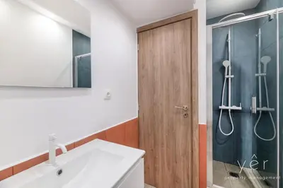 a bathroom with a sink and a wooden door at Shell-Charm w/Sea View & Parking in Piraeus