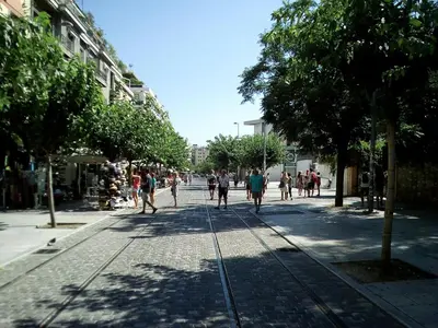 a group of people walking down a street at 3-Generations Athenian home in Athens