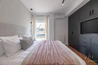 a bedroom with a large bed with a flat screen tv at Luxury Flat w/2Bath - Private Parking @Pasalimani in Piraeus