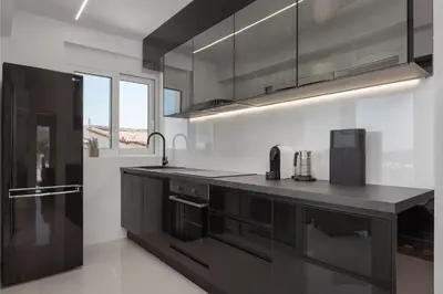 a kitchen with black cabinets and a counter top at Athenian Riviera Penthouse Apartment in Varkiza