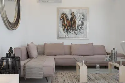 a living room with a couch and a painting of horses at Athenian Riviera Penthouse Apartment in Varkiza
