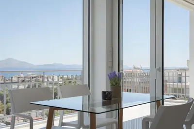 a dining room with a glass table and white chairs at Athenian Riviera Penthouse Apartment in Varkiza