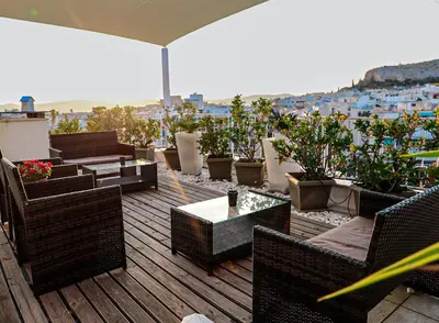 a balcony with chairs and tables and potted plants at Bachelor Penthouse with Roof Garden access, 15 m walk to Acropolis in Athens