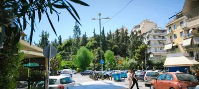 a busy city street with cars and people on the sidewalk at Central Apartment in Pangrati - Opp Pangrati Grove in Athens