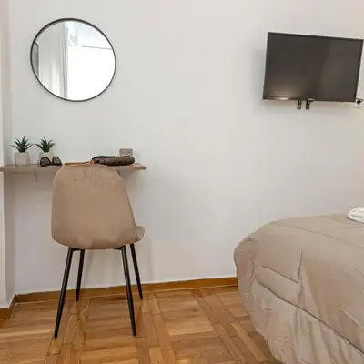 a chair in a room with a mirror and a bed at Cozy Apartment in Kallithea in Athens