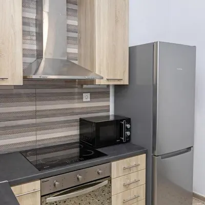 a kitchen with a microwave and a refrigerator at Cozy Apartment in Kallithea in Athens