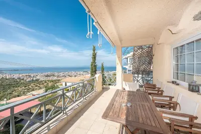 a balcony with a wooden table and chairs at Luxury Home with Jacuzzi and Spectacular Sea Views for 8 Guests in Athens
