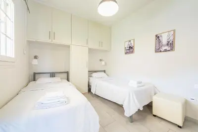 two beds in a room with white walls at Luxury Home with Jacuzzi and Spectacular Sea Views for 8 Guests in Athens