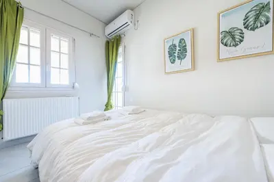 a white bed in a white room with a window at Luxury Home with Jacuzzi and Spectacular Sea Views for 8 Guests in Athens