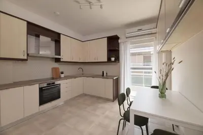 a kitchen with white cabinets and a table and chairs at Luminous 3BR Apartment in Cholargos by UPSTREET in Athens