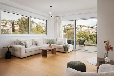 a living room with a white couch and large windows at Athenian Riviera Elegant Residence in Athens