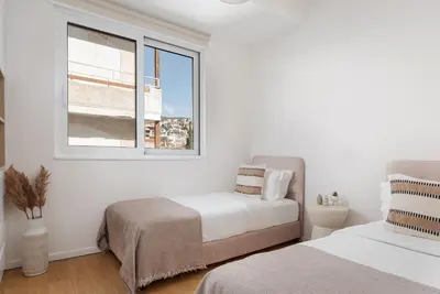 a bedroom with two beds and a window at Athenian Riviera Elegant Residence in Athens