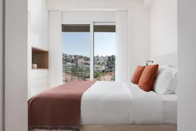 a white bedroom with a large bed and a window at Athenian Riviera Elegant Residence in Athens