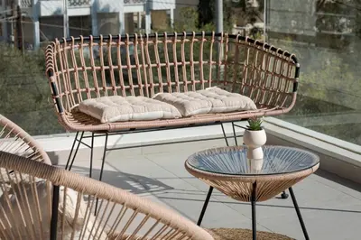 a wicker bench sitting on a balcony with a table at Athenian Riviera Elegant Residence in Athens