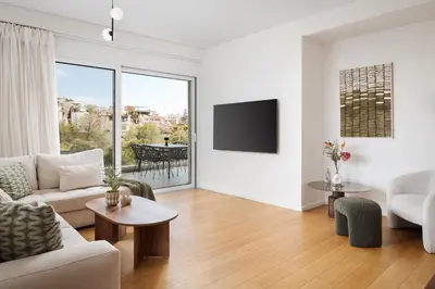 a living room with a couch and a tv at Athenian Riviera Elegant Residence in Athens