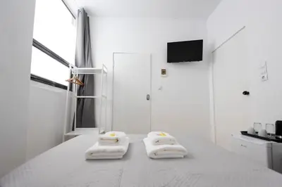 a white bedroom with two towels on a bed at Ati-Key Residence in Athens
