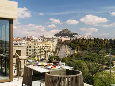 a balcony with a table and chairs and a view of a city at Anthology of Athens, The Leading Hotels of the World in Athens