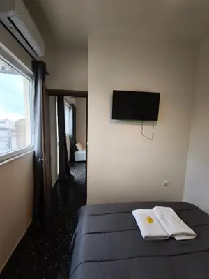 a bedroom with a bed and a flat screen tv at Liberal Mini Rooms & Suites in Athens