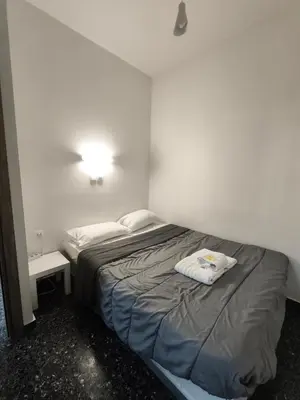 a small bedroom with a bed and a lamp at Liberal Mini Rooms & Suites in Athens