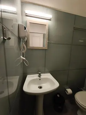 a bathroom with a sink and a phone on the wall at Liberal Mini Rooms & Suites in Athens