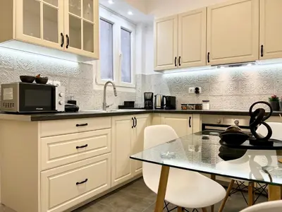 a kitchen with white cabinets and a table at Acropolis Signature Apartment in Athens