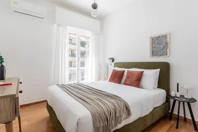 a white bedroom with a large bed with red pillows at Acropolis Sunlight 2BR Apartment by UPSTREET in Athens